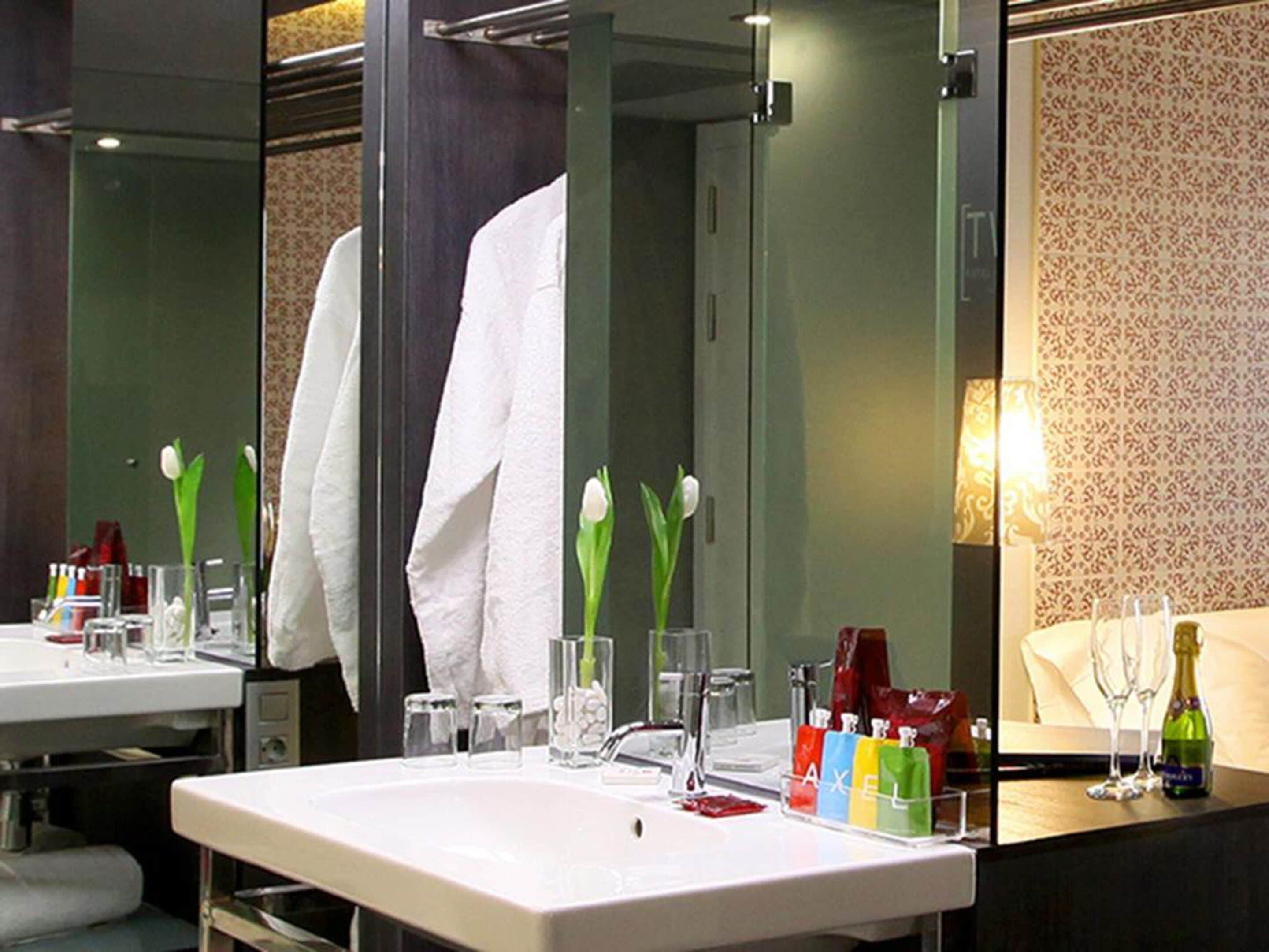 A bathroom with a large mirror, a white sink, and toiletries.