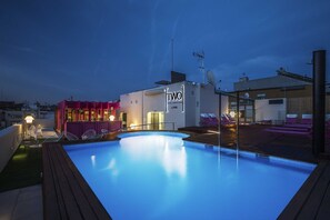 Una piscina en la azotea con sillones de descanso y un edificio con la leyenda 'TWO HOTEL BARCELONA'.
