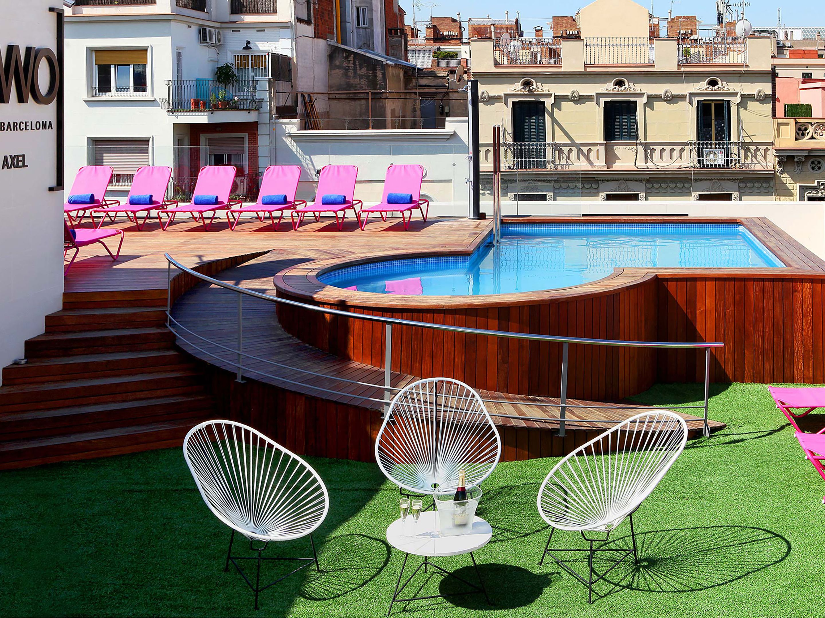 A rooftop pool area with a wooden deck, a swimming pool, and several lounge chairs.