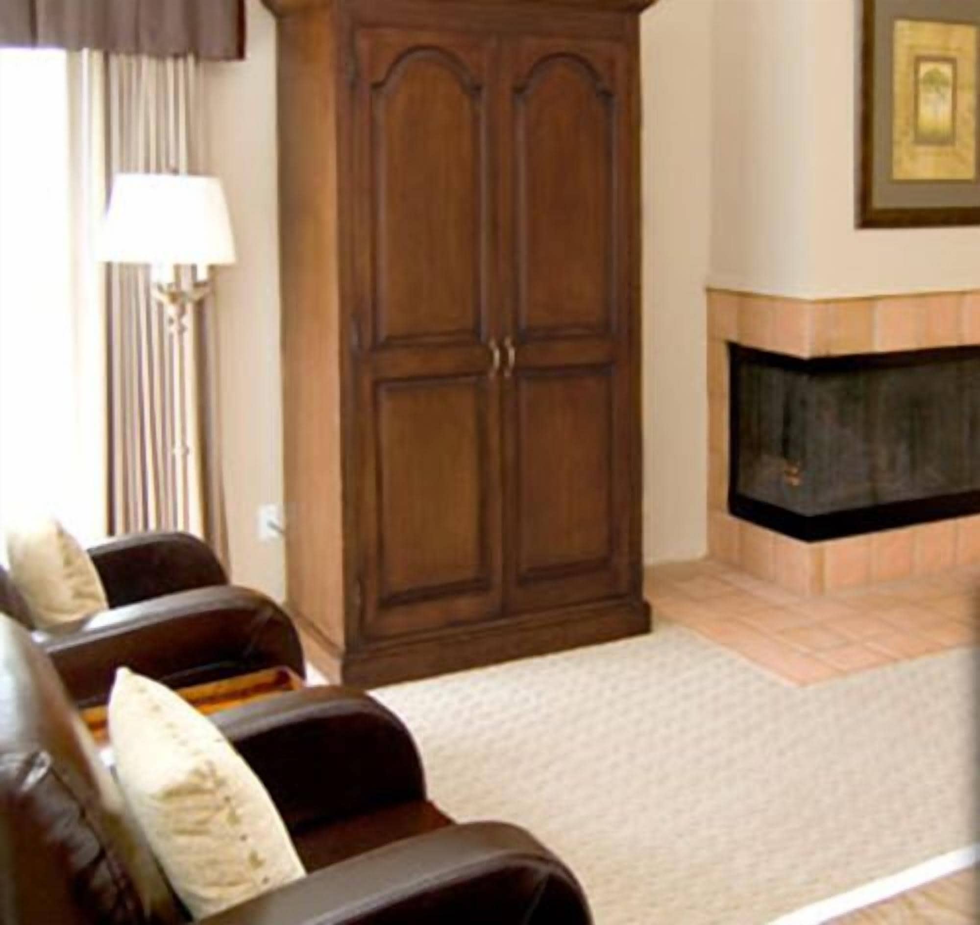 A living room with a brown leather sofa, a large wooden cabinet, and a fireplace.