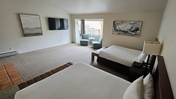 Habitación de hotel con dos camas, un televisor, un cuadro y un balcón con una silla.
