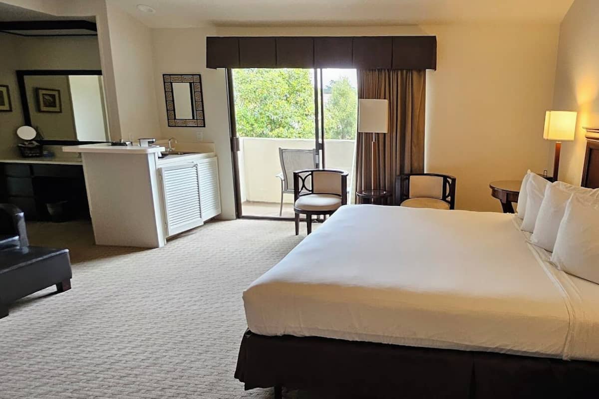 Une chambre d’hôtel avec un grand lit, un bureau avec un téléphone, une chaise et une vue sur l’extérieur.