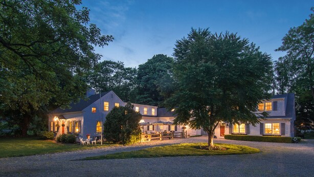 A large, two-story house with a gravel driveway and a well-maintained lawn. - The Parsonage Inn (Orleans)