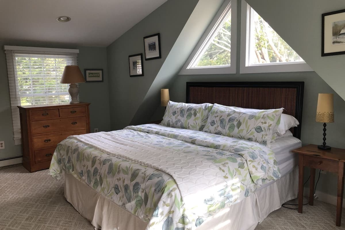A bedroom with a bed, dresser, nightstands, and a window with blinds.