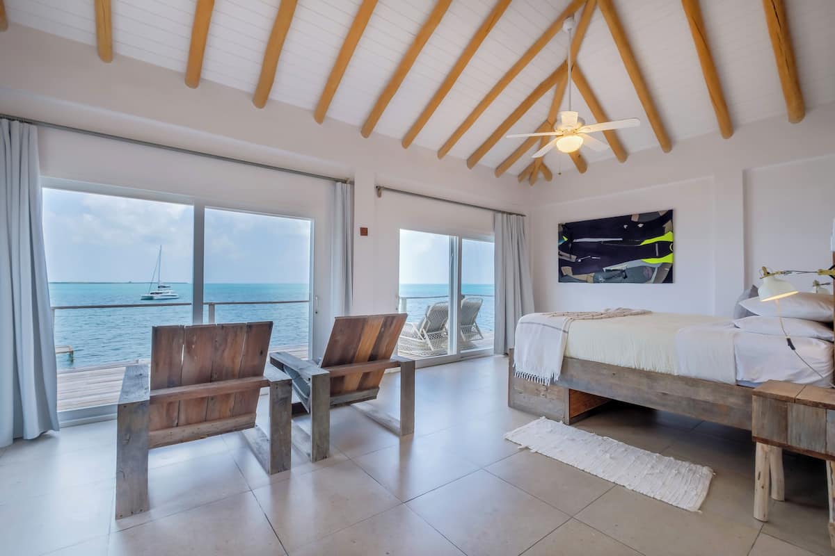 A bedroom with a large window, wooden furniture, a bed, and a ceiling fan.