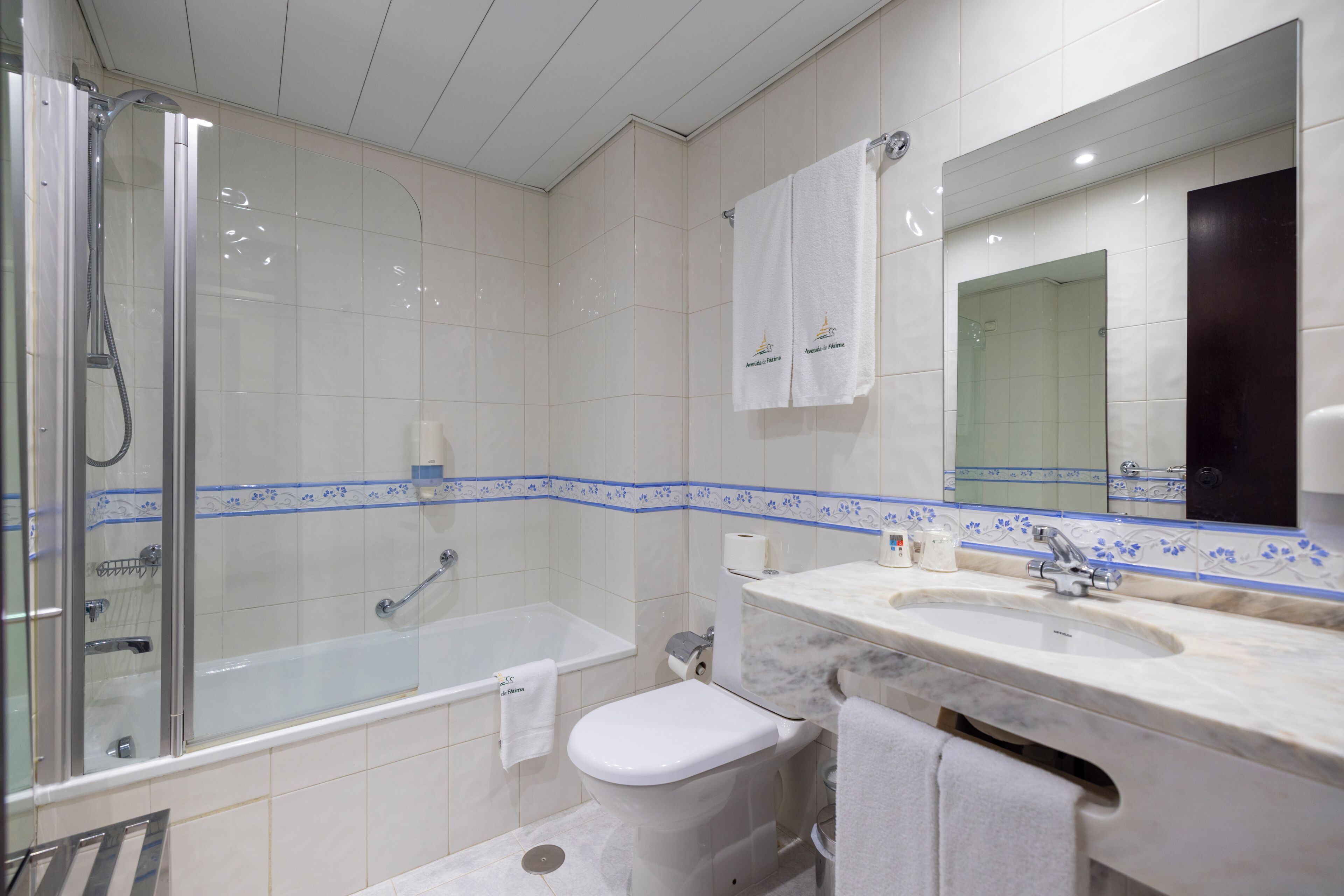 Un baño con ducha de vidrio, bañera, inodoro y lavamanos con espejo.