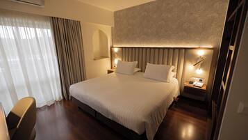 A modern hotel room with a large bed, bedside tables, a desk, and a chair.