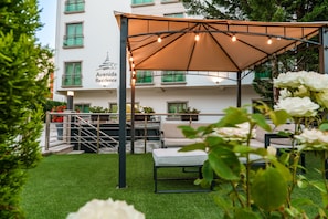 A rooftop terrace with a pergola, outdoor seating, and a view of a building with balconies. - Avenida de Fátima (Ourem)