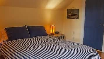 Un dormitorio con una colcha a rayas, dos lámparas de noche y una puerta.