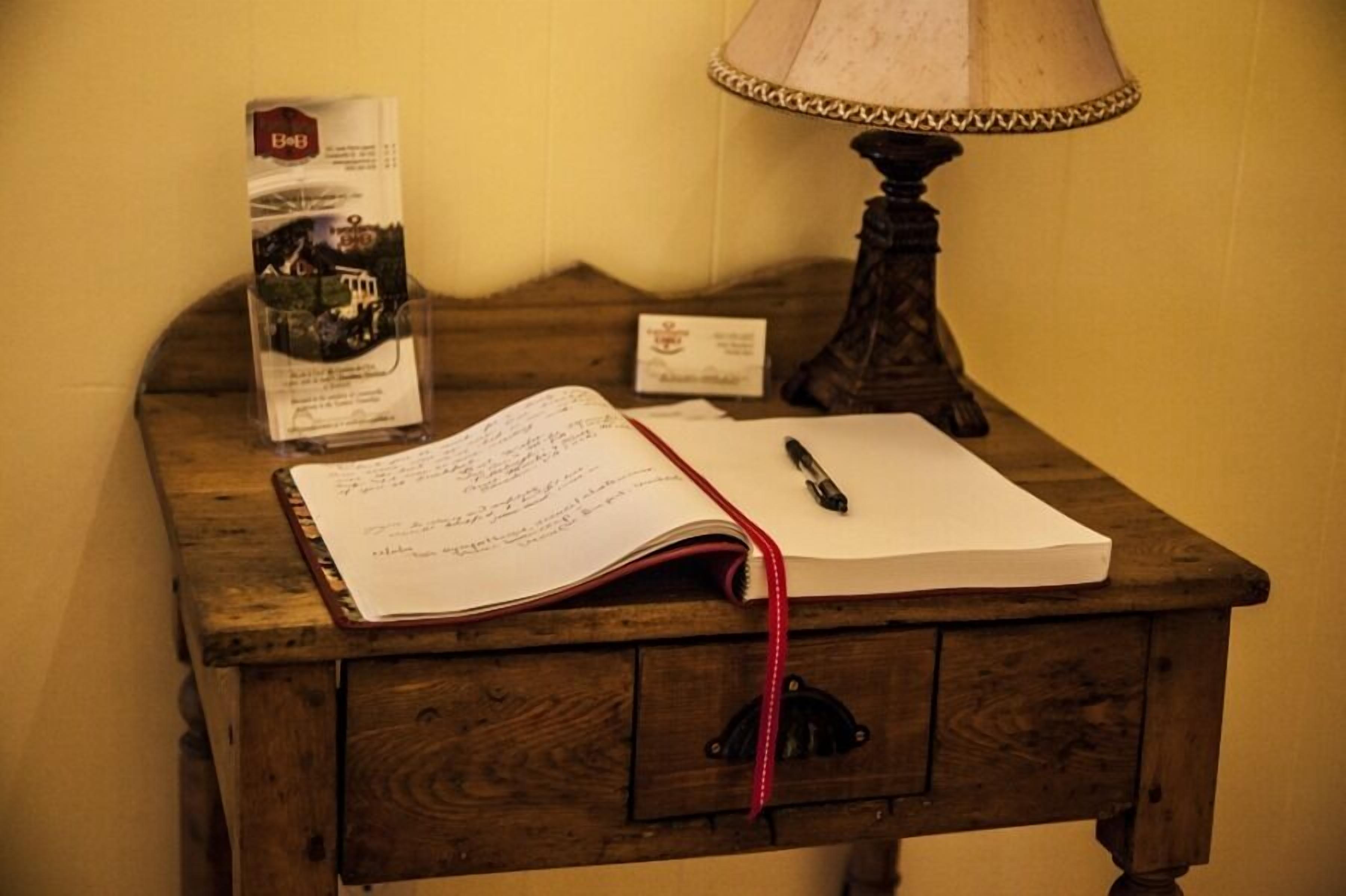 A wooden desk with a lamp, a notebook, and a brochure.