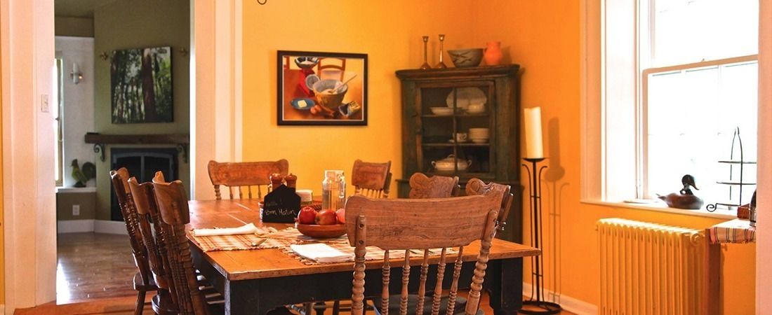 Un comedor con una mesa de madera, sillas y un aparador. Se ve una ventana con vistas al exterior.