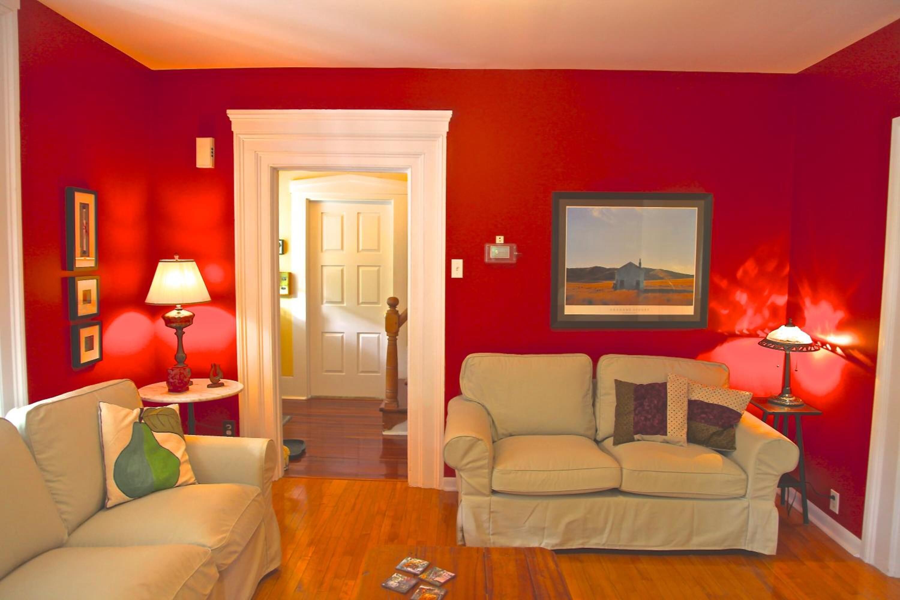 Una sala de estar con dos sofás color beige, una mesa de centro de madera y paredes rojas.