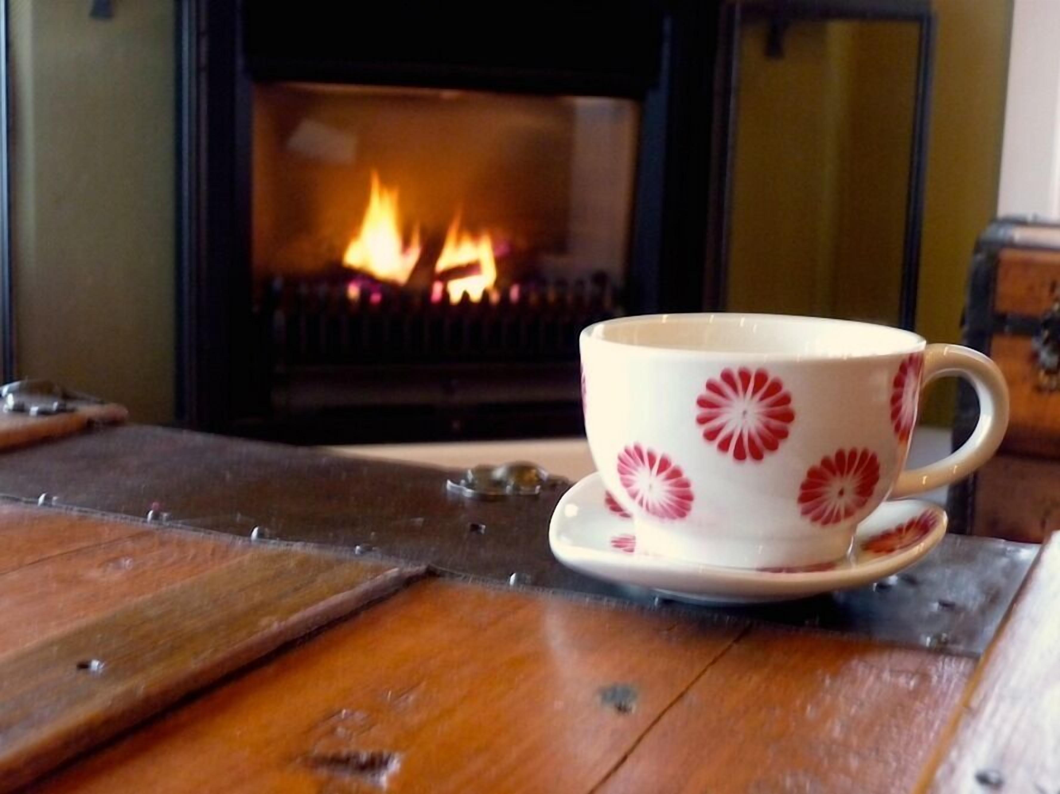 A cup with a floral pattern on a wooden table near a fireplace.