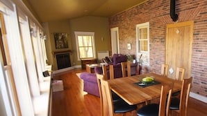 Un comedor amplio con pared de ladrillo, mesa y sillas de madera.