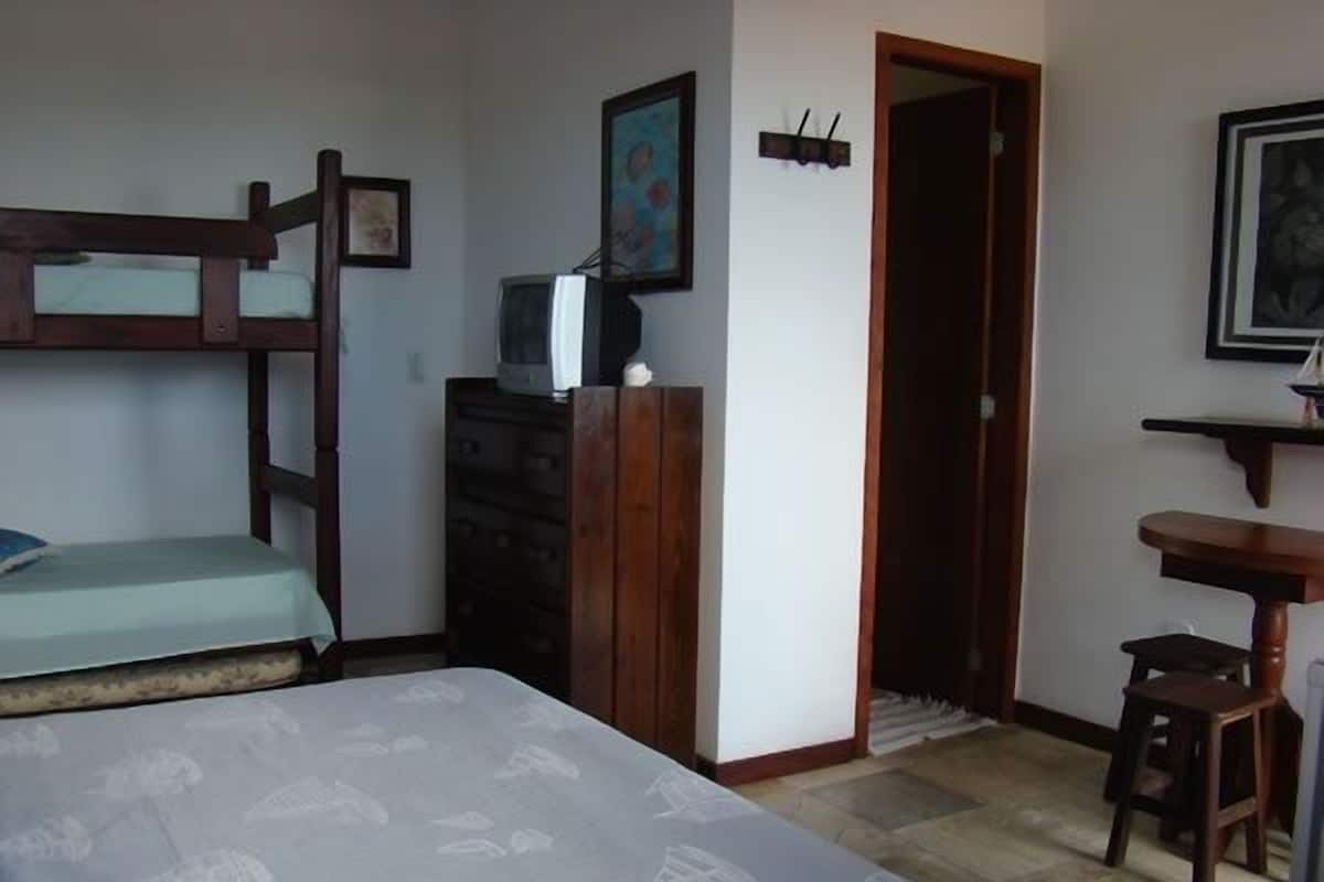 Ein Schlafzimmer mit einem Etagenbett, einem Schreibtisch mit Stuhl, einem Schminktisch und einer Tür zu einem anderen Raum.