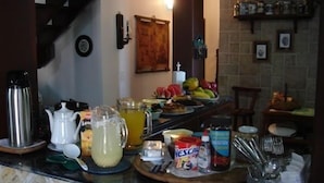 A kitchen counter with various food items, a coffee maker, and a fruit bowl. - Pousada Casa do Telhado Verde (Cabo Frio)