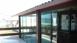 A modern building with large glass doors leading to a covered outdoor area with a tiled floor. - Pousada Casa do Telhado Verde (Cabo Frio)