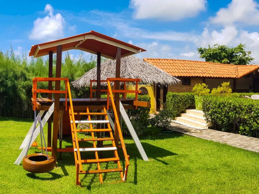 A playground with a slide and a climbing structure, surrounded by well-maintained grass and plants.