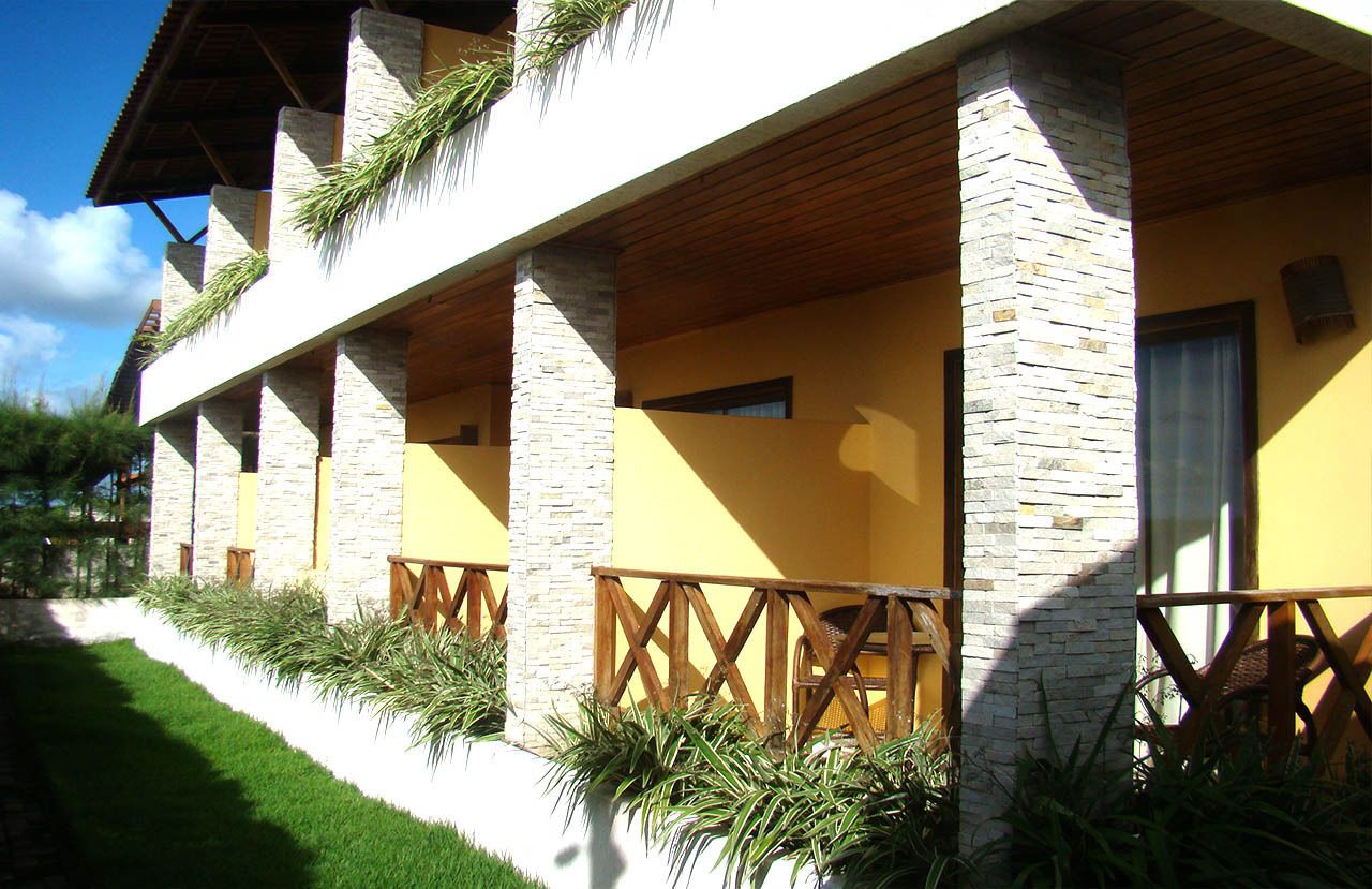 A building with a yellow facade, stone pillars, and wooden beams.