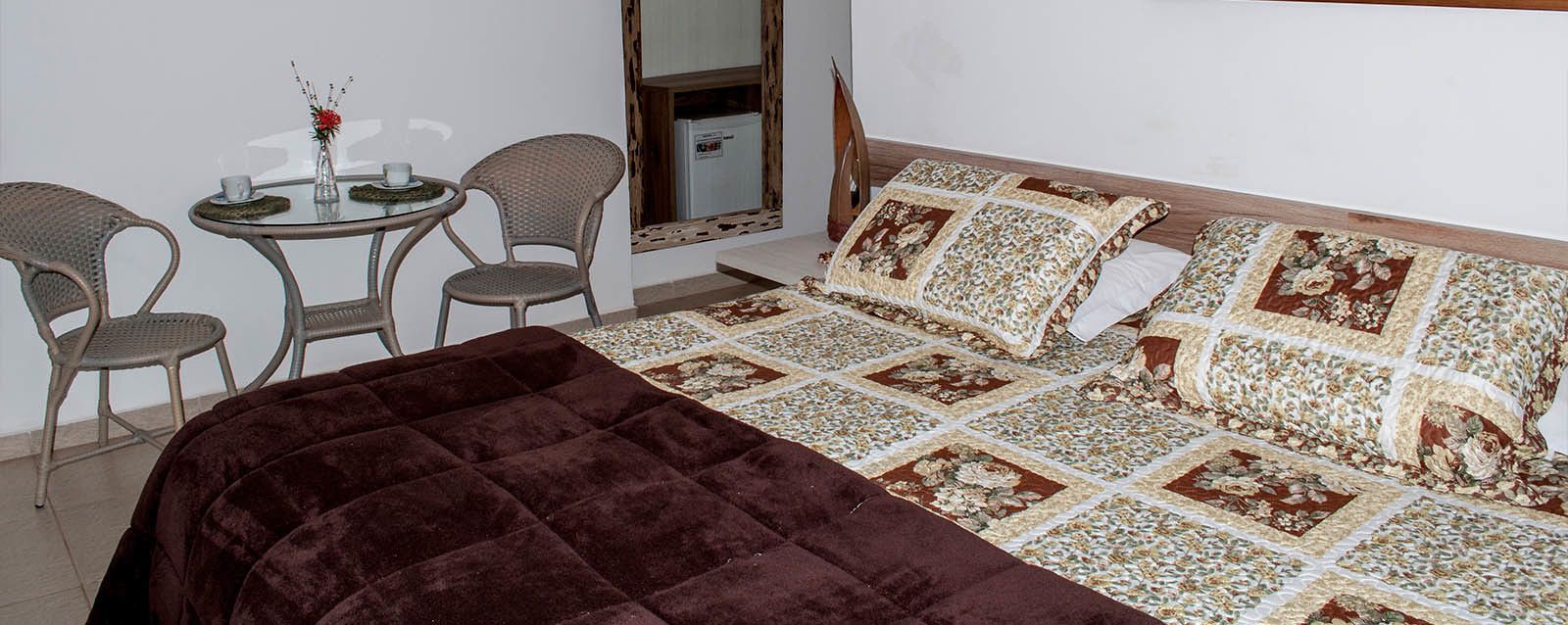 A bedroom with a bed, a small round table with chairs, and a mirror.