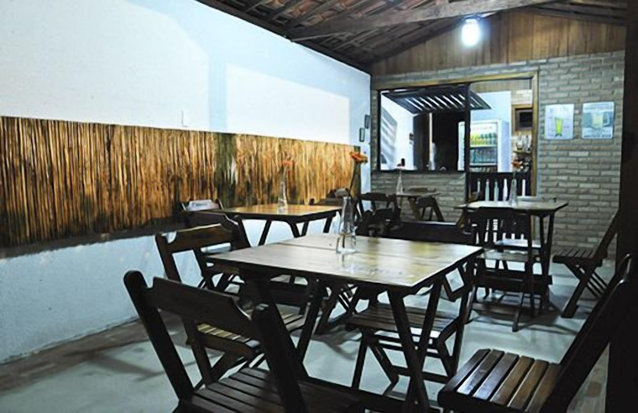 Un restaurante con mesas y sillas de madera, un muro de ladrillo y una planta colgante.