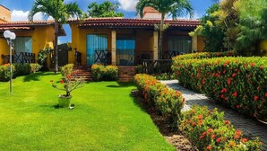 Un edificio de dos pisos con piscina, rodeado de jardines cuidados y un cielo despejado.