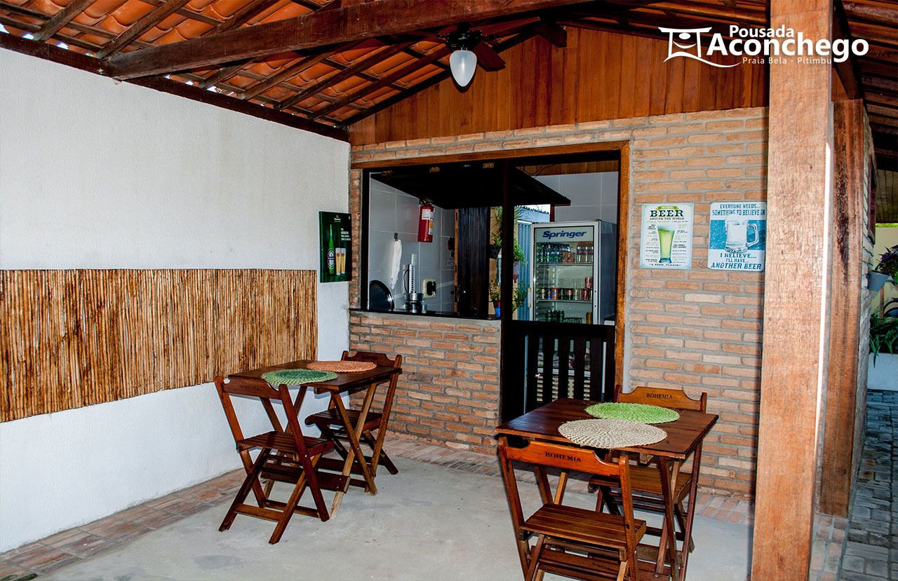 Un patio al aire libre con mesas y sillas de madera, un muro de ladrillo y un cartel de cerveza Springer.