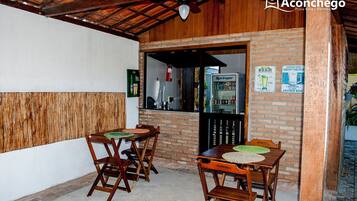 Un patio al aire libre con mesas y sillas de madera, un muro de ladrillo y un cartel de cerveza Springer.
