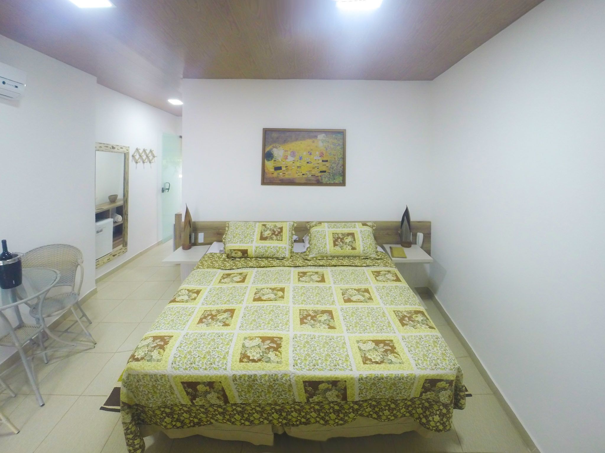 A bedroom with a bed, a chair, a small table, and a painting on the wall.