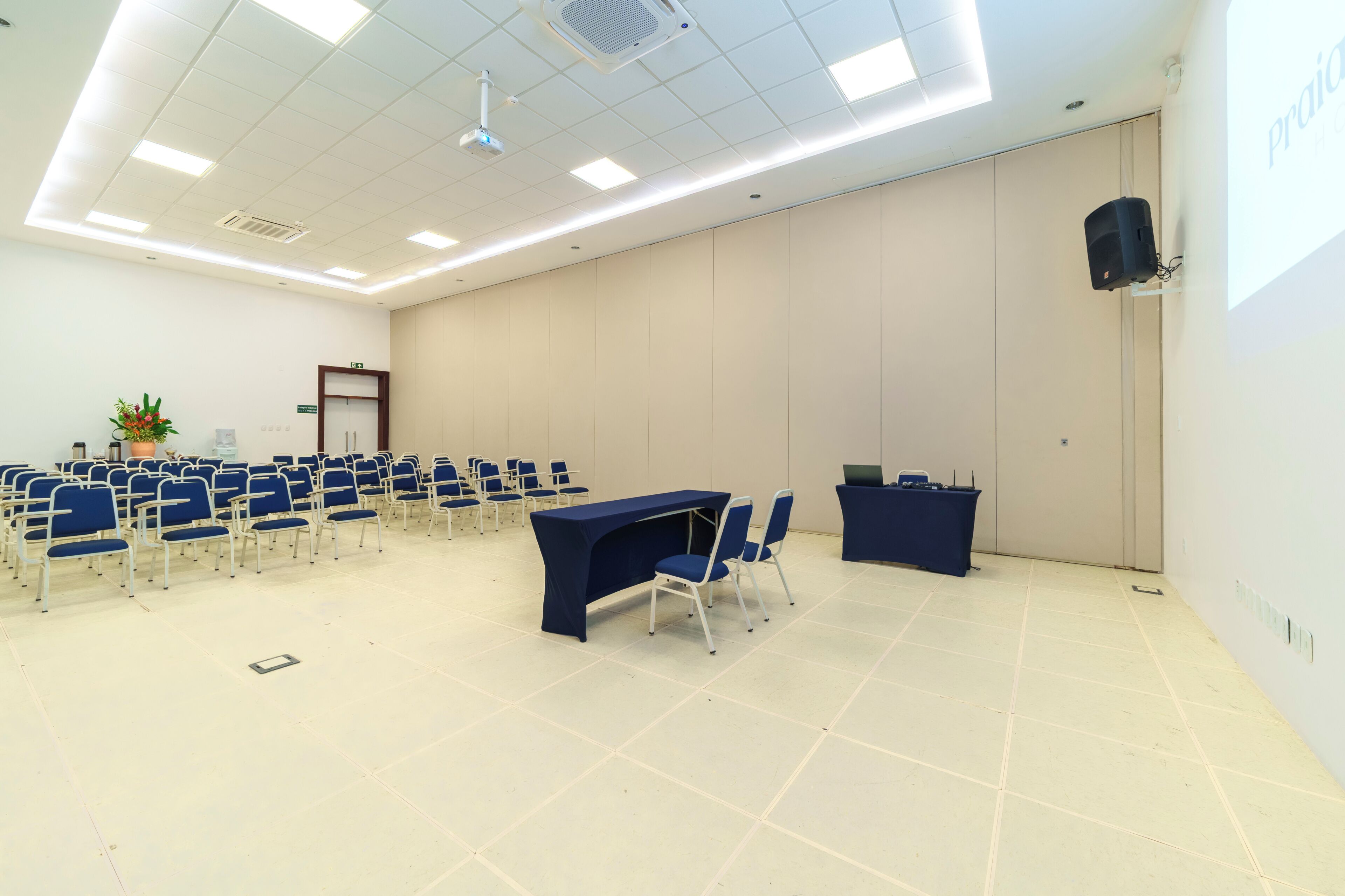 Un salón de conferencias con filas de sillas, un atril y un proyector.