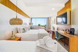 Habitación de hotel con dos camas, un escritorio, un televisor y un balcón con vistas.