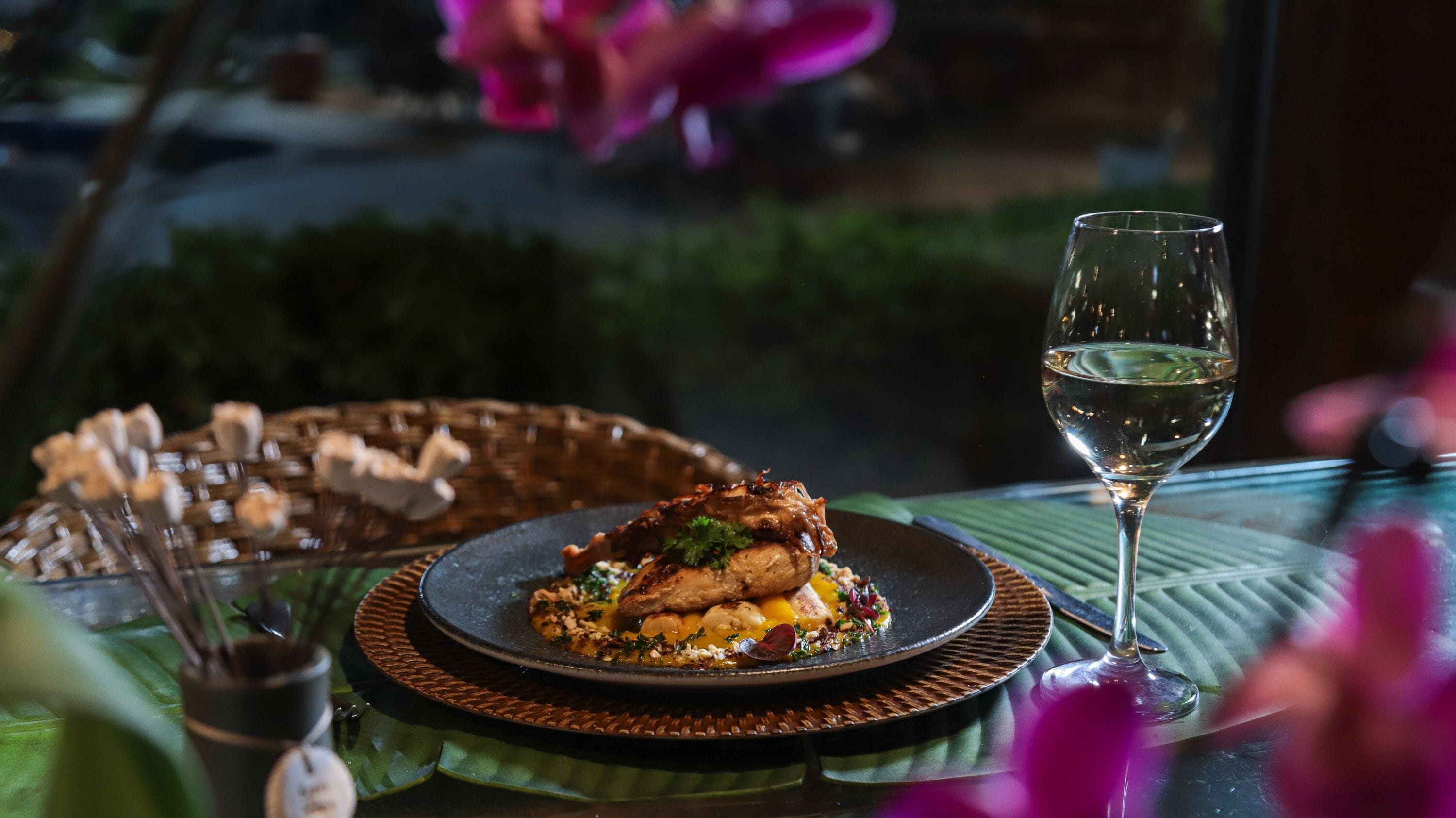 Une table avec une assiette de nourriture, un verre de vin et un panier de pain.