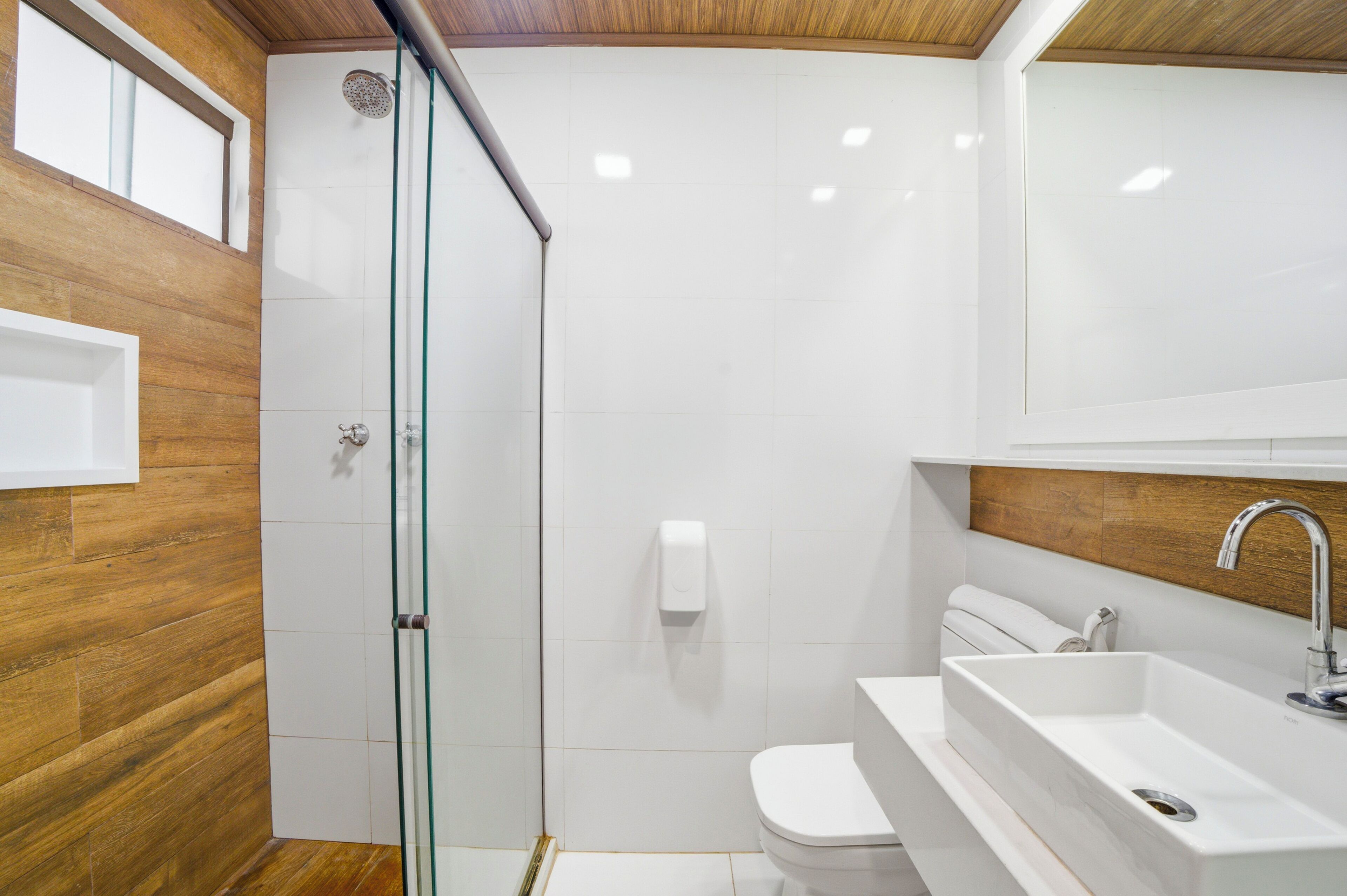 Een moderne badkamer met een douchecabine van glas, een wit toilet en een ingebouwd wastafelmeubel.