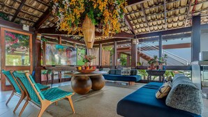 A spacious indoor area with a large TV, comfortable seating, and a decorative hanging plant.