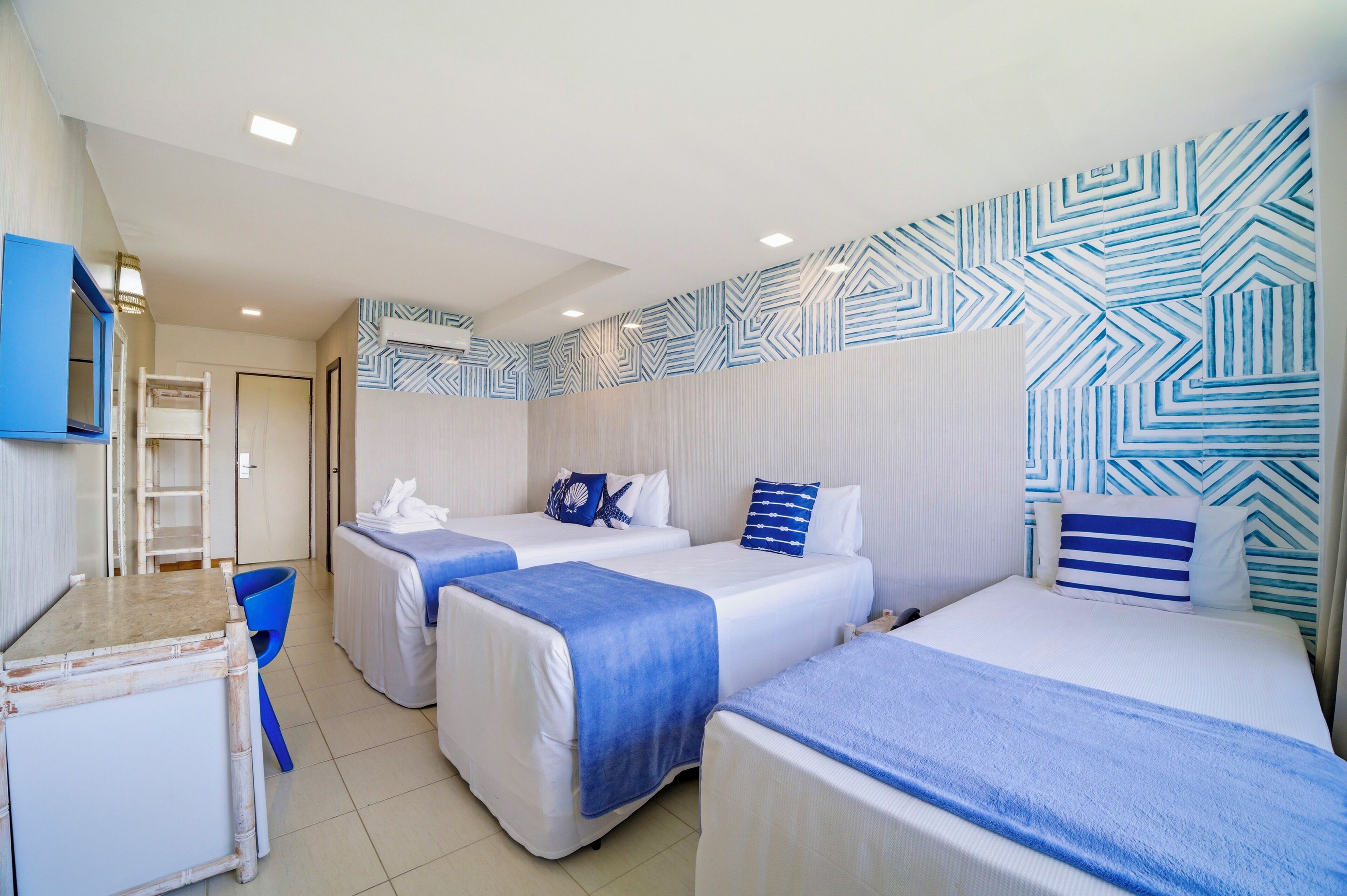 Habitación de hotel con tres camas, un escritorio y una silla.