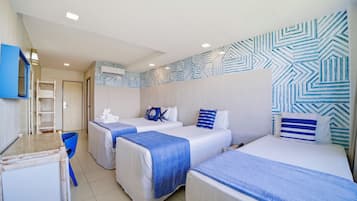 A hotel room with three beds, a desk, and a chair.