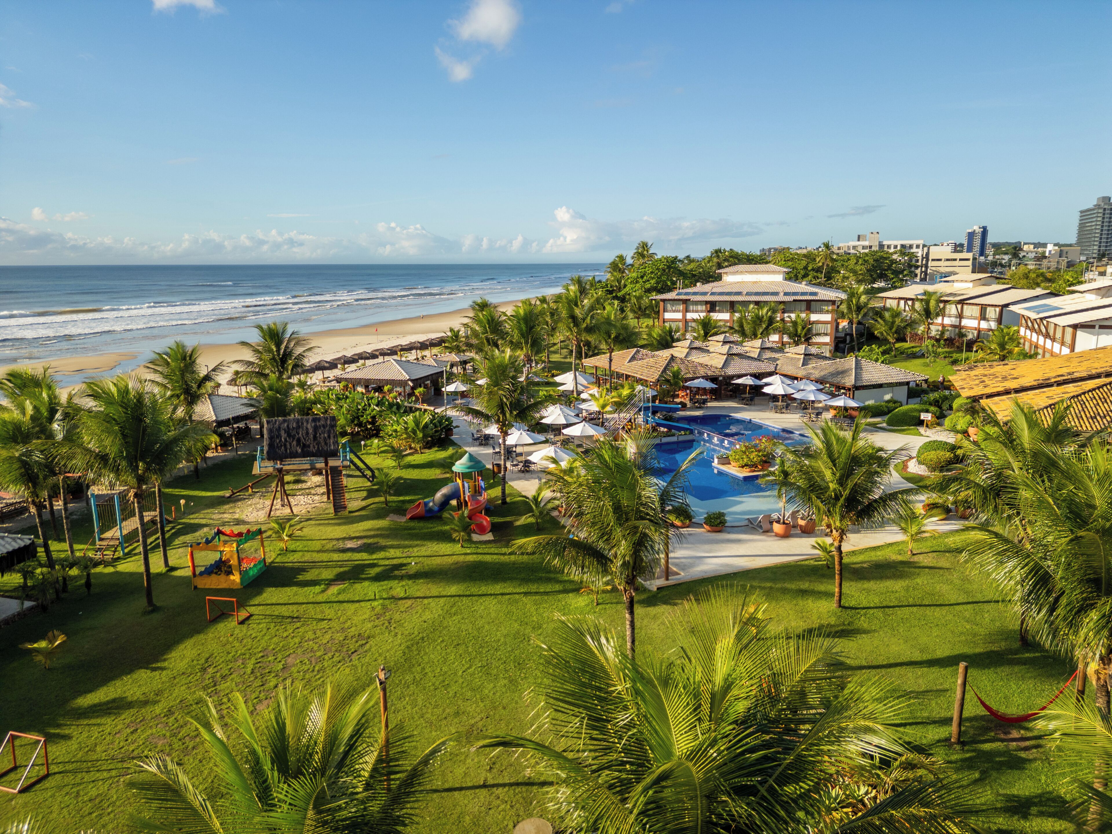 A resort with a swimming pool, beach, and palm trees.