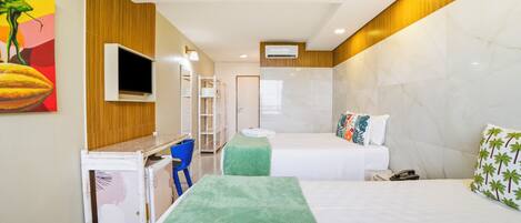Una habitación de hotel con cama, escritorio, silla, televisor y baño.