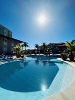 Una piscina al aire libre, sombrillas, tumbonas