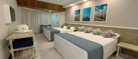 A hotel room with two beds, a desk, and a chair. There are three paintings on the wall.