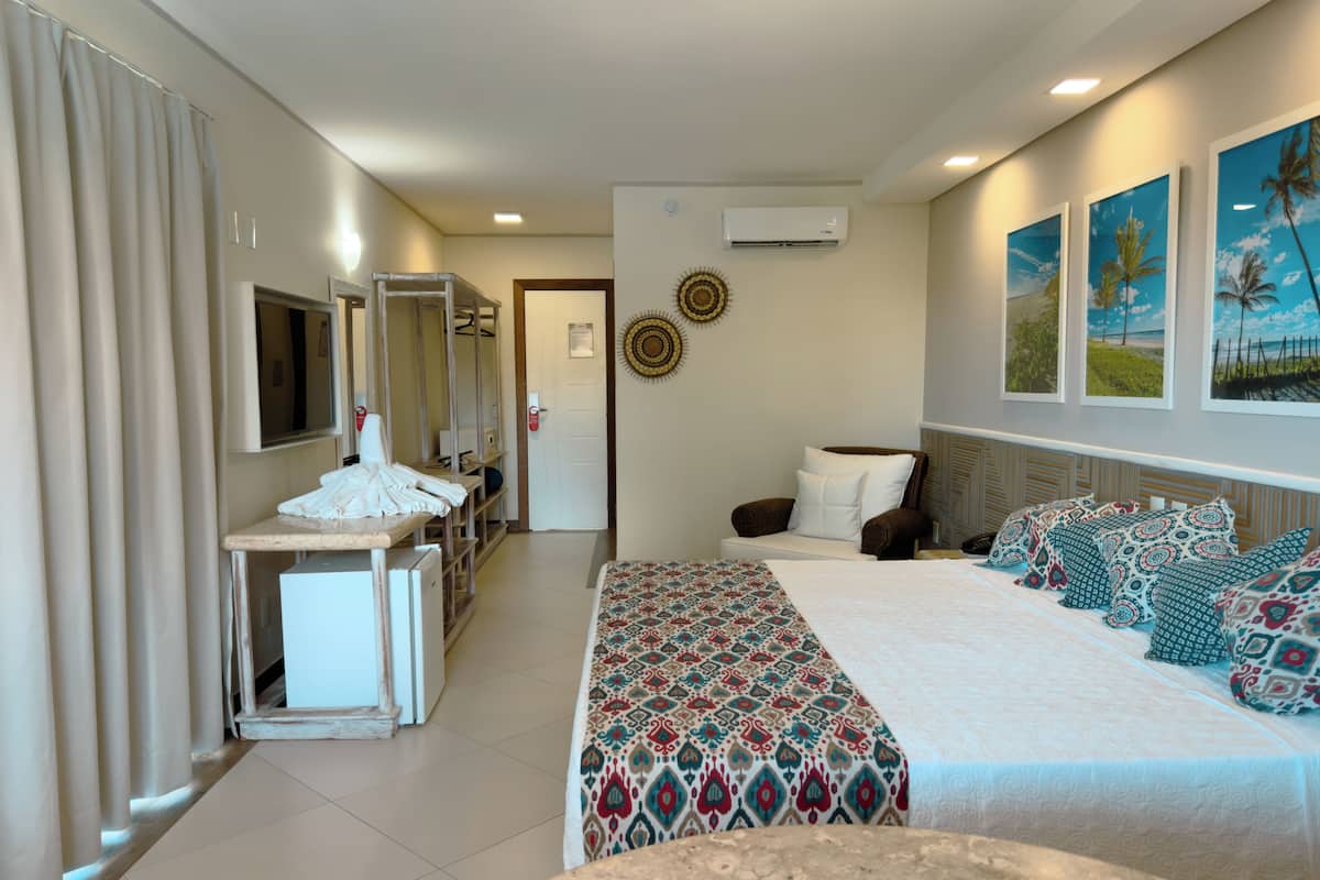 A hotel room with a bed, a desk, a chair, a wardrobe, and a bathroom.