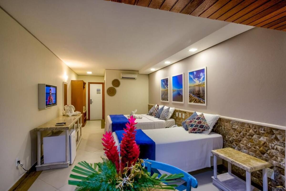 Habitación de hotel con dos camas, un escritorio, una mesita pequeña y un banco.