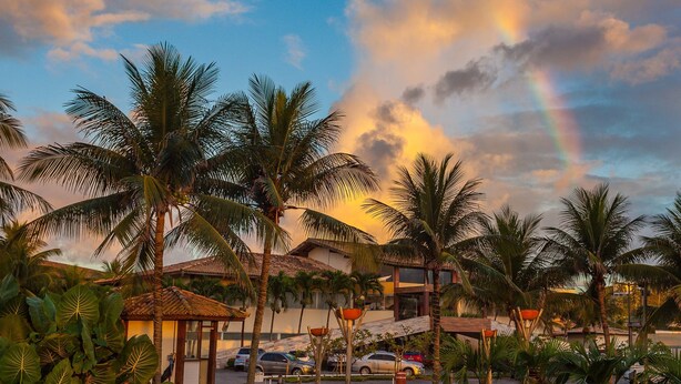 Un resort tropical con palmeras, un pabellón y un edificio de techo a teja.