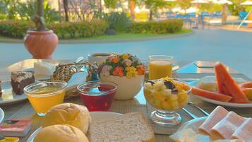 Una mesa dispuesta con diferentes productos para el desayuno, como pan, fruta y bebidas.