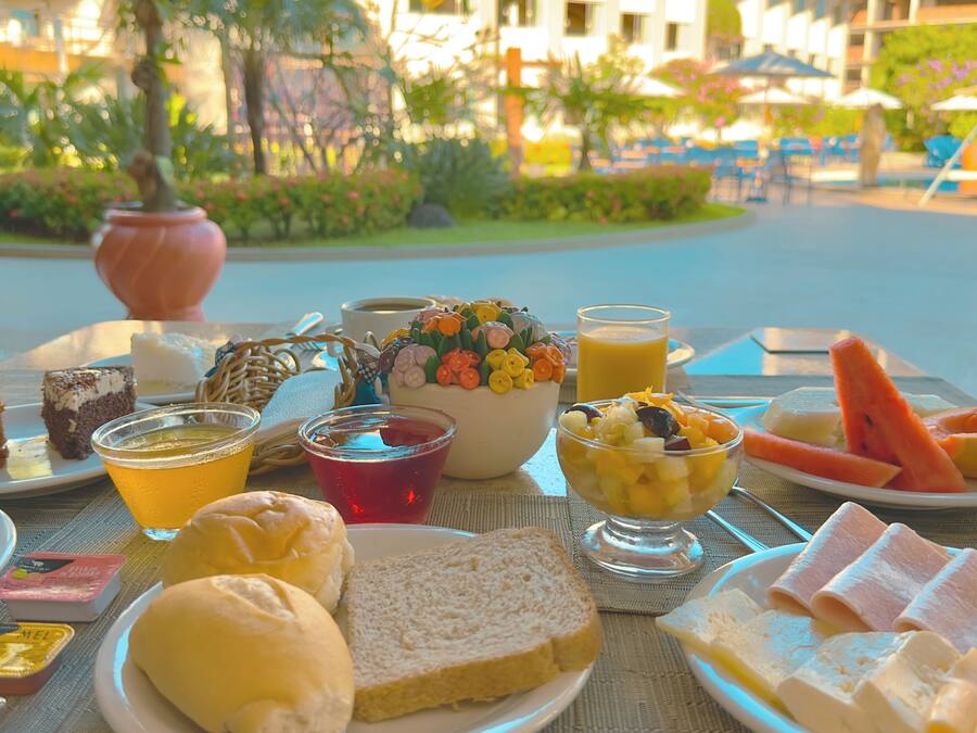 Una mesa dispuesta con diferentes productos para el desayuno, como pan, fruta y bebidas.
