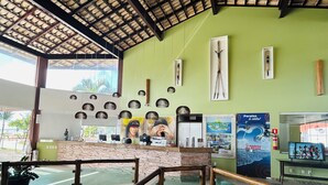 Un área de recepción con pared verde, techo de madera y barandilla de vidrio.