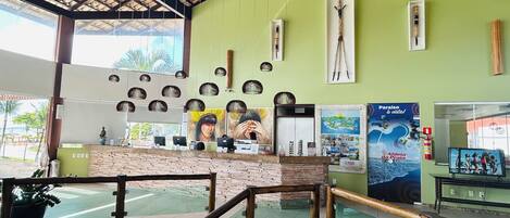 A reception area with a green wall, wooden ceiling, and a glass railing.