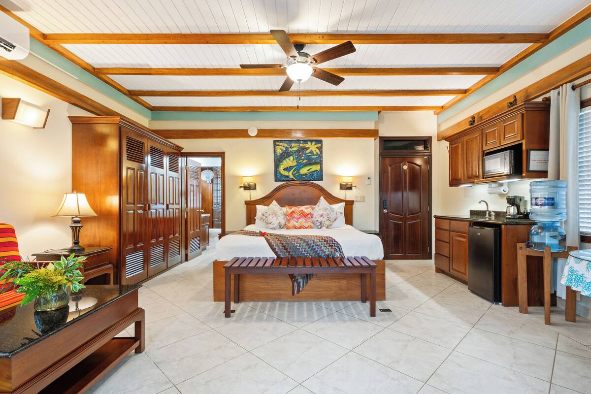 A spacious bedroom with a large bed, wooden headboard, and a ceiling fan.