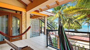 A balcony with a hammock, a view of the beach, and a staircase leading to an upper level. - Buttonwood Belize (Hopkins)