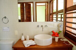 A bathroom with a white sink, wooden countertop, and a mirror above it.